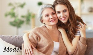 Grandmother and Granddaughter Embracing On Couch